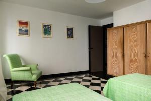 - une chambre avec 2 lits, une chaise verte et une armoire dans l'établissement San Matteo 23, à Gênes