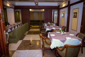 a dining room with tables and chairs in a restaurant at The Hotel Airport in Vadodara