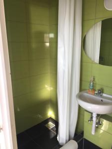 a green bathroom with a sink and a mirror at Cuki Apartmanok in Si&oacute;fok