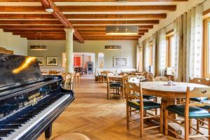 a room with a piano and tables and chairs at SEINZ Wisdom Resort - Bio-Hotel vegan-vegetarisch in Bad Kohlgrub
