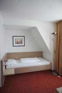 ein weißes Bett in einem Zimmer mit einer Treppe in der Unterkunft Gästehaus Andrea in Stuttgart