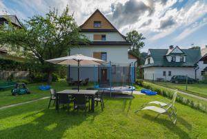 een achtertuin met een tafel, een parasol en een trampoline bij Pokoje gościnne "U Teresy" in Krościenko