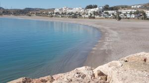 a beach with rocks and the water and buildings at Hostal San Andres in Carboneras