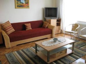 バラトンフレドにあるLiliom Apartments Balatonfüredのリビングルーム(赤いソファ、コーヒーテーブル付)