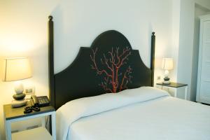 un letto con testiera nera e corallo di Hotel Cutimare - Aeolian Charme ad Acquacalda