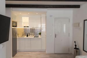 a kitchen with white cabinets and a white door at Cosy Flat - City Center - Parking free in Málaga
