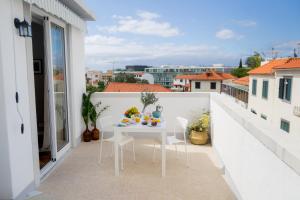 Cozy apartment - Historic Center of Funchal, Madeira في فونشال: شرفة بيضاء عليها طاولة وكراسي