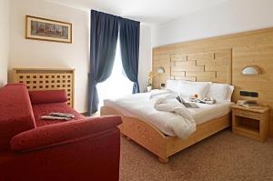 a bedroom with a bed and a red chair at Hotel Europa in Madonna di Campiglio