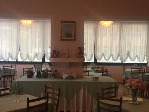 a dining room with a table and chairs and windows at Hotel Laila in Cesenatico