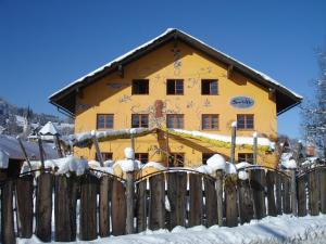 ein gelbes Haus mit einem Zaun im Schnee in der Unterkunft Schiff Bihlerdorf - Hostel in Bihlerdorf