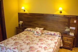 a bedroom with a bed with a wooden headboard at Conjunto Hotelero La Pasera in Soto de Cangas