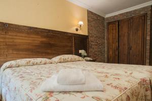 um quarto com uma cama grande e uma cabeceira em madeira em Conjunto Hotelero La Pasera em Soto de Cangas