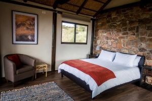 a bedroom with a bed and a stone wall at Ikwanitsha Lodge in Paterson