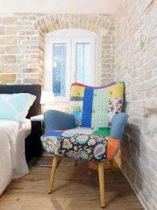 a colorful chair in a room with a bed at Studio apartment Milla in Split