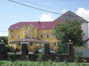 a yellow house with a fence in front of it at Apollon in Mukacheve