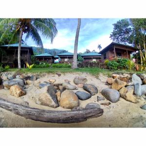 a pile of rocks in the sand in front of a house at ABC Chalet Tioman in Tioman Island