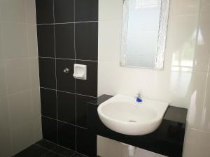 a bathroom with a white sink and a mirror at Happy Holiday home in Balik Pulau