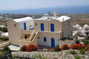 a white house with blue doors on a hill at Panorama Oia Apartments in Oia