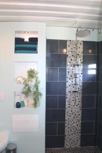 un bagno con doccia con parete piastrellata nera di Buddha Bleu a Sainte-Luce