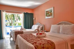 two beds in a hotel room with two swans on them at Bay Gardens Inn in Gros Islet