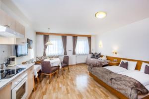 a hotel room with a bed and a kitchen at La Majon Apartments in Selva di Val Gardena