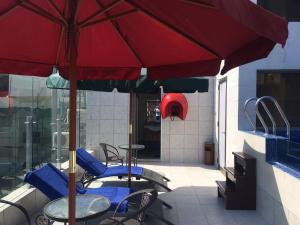 Midtown Hotel & Suites في بيروت: فناء به طاولات وكراسي ومظلة حمراء