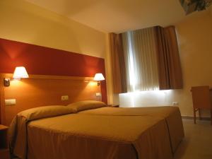 a hotel room with a bed and a window at Hostal Ciudad de Cáparra in Carcaboso