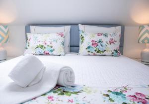 uma cama branca com flores e almofadas em Real Holidays Nazaré em Nazaré