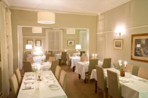 a dining room with white tables and chairs with lights at Peak Weavers in Leek