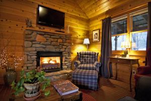 a living room with a fireplace and a chair at Mountain Springs Cabins in Candler