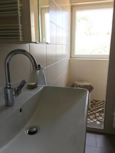 Un lavabo blanco en un baño con ventana. en Ferienhaus Scholien, en Otterndorf 59 fotos más