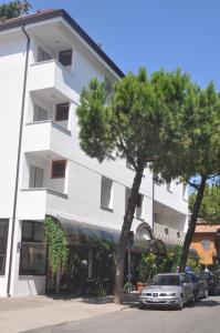 un edificio bianco con macchine parcheggiate di fronte di Hotel Villa Candia a Lignano Sabbiadoro