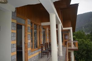 Himalaya Cottage في مانالي: شرفة منزل مع كراسي ونوافذ