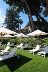 een groep witte stoelen en parasols op het gras bij La Casa di Anny camere di Charme Citr 8027 in Diano Marina