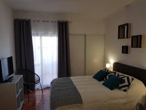 阿爾布費拉的住宿－Appartement piscine Albufeira 205C，一间卧室设有一张床、一台电视和一个窗口。