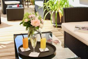 a table with a vase with flowers and glasses at Logis Hotel - Le Charleston in Le Mans