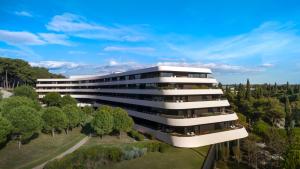 un edificio de oficinas con árboles delante de él en Lone Hotel by Maistra Collection en Rovinj