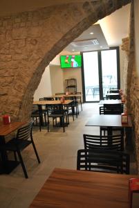 a restaurant with tables and chairs and a stone wall at Hostal Universitat in Cervera