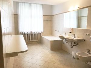 bagno con 2 lavandini, vasca e lavandino di Manzoni Rooms a Merano