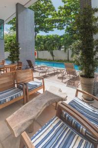 un patio con bancos de madera y una piscina en Excelente Flat em Boa Viagem 2 quartos Beach Class Ideal para Família ou Negócios NOB2105, en Recife