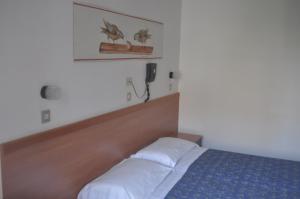 Schlafzimmer mit einem Bett und einem Telefon an der Wand in der Unterkunft Hotel Villa Candia in Lignano Sabbiadoro