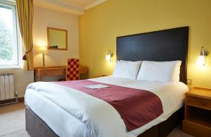 Roebuck by Greene King Inns في فورست رو: غرفة نوم بسرير كبير في غرفة الفندق