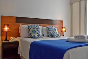 1 dormitorio con 1 cama grande con manta azul en Giuseppe Suites Hotel, en Asunción