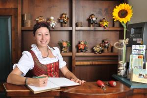 una mujer sentada en un escritorio con un libro en Hotel Saigerhütte, en Olbernhau