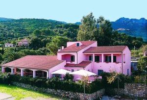 una casa rosa sentada en la cima de una colina en Appartamenti Le Spiagge, en Marciana Marina