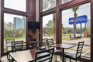 un restaurante con mesas, sillas y ventanas en Americas Best Value Inn Medical Center Downtown en Houston
