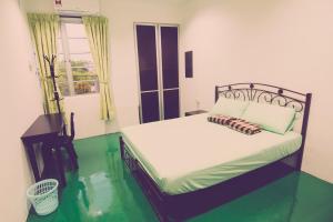 a bedroom with a bed with green floors and a window at The Haven Inn in Melaka