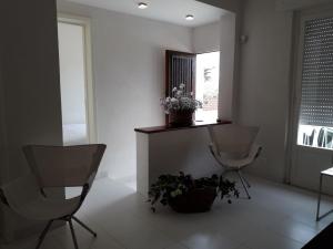 ein Wohnzimmer mit 2 Stühlen und einer Topfpflanze in der Unterkunft La Casa Di Roy in Pizzolungo