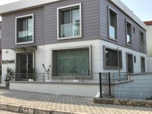 una casa grigia e bianca con una recinzione di fronte di EVN Hotel a Çeşme