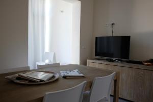 a dining room table with white chairs and a television at Acqua Dolce in Rio Marina